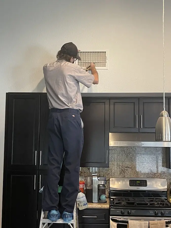 Technician inspecting an air vent during HVAC service in Accokeek